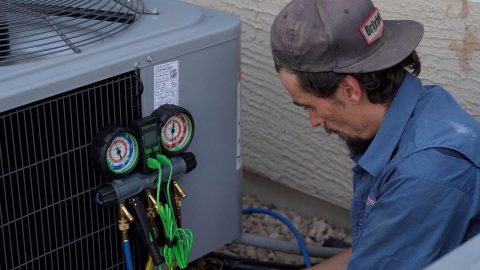 Air Conditioning Tech Hooks Up Gauges to AC unit for Pressure check.