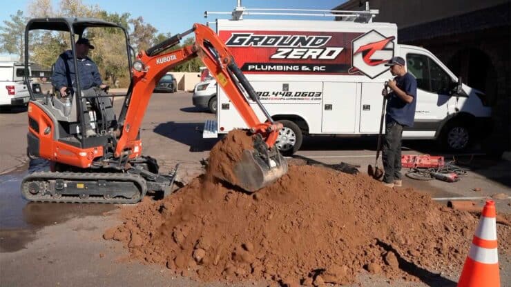 Using the back-ho to locate a broken pipe for repair